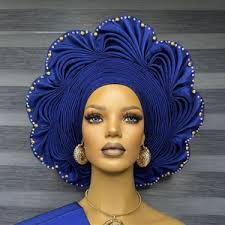 A blue Nigerian gele headwrap styled on a mannequin, showing its elegant shape and design.